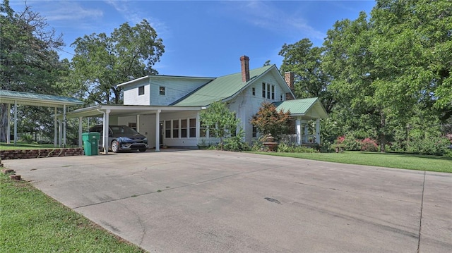 view of front of house with a front yard, concrete driveway, a carport, and metal roof