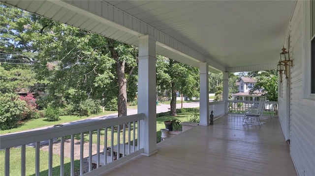 wooden deck with a lawn and covered porch