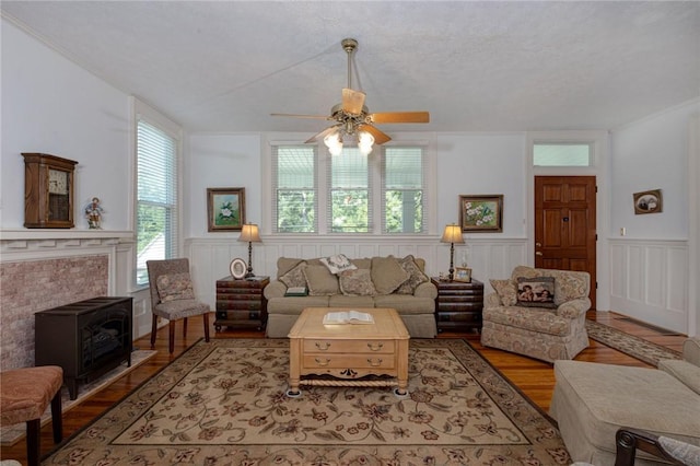 living room with a wainscoted wall, wood finished floors, and a ceiling fan