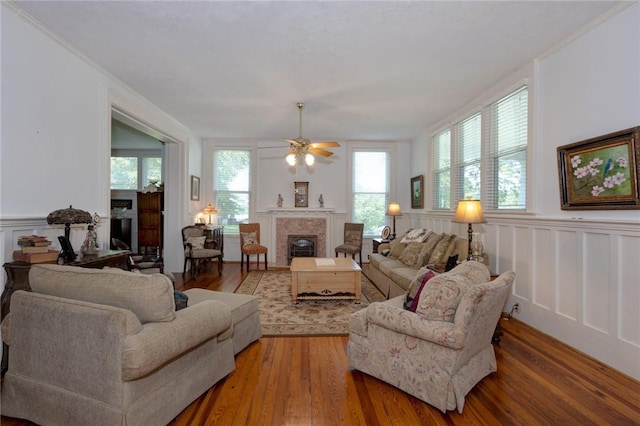 living area featuring a decorative wall, wood finished floors, wainscoting, and a tile fireplace