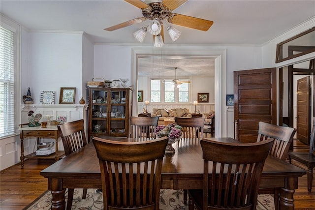 dining area with wood finished floors, ornamental molding, and wainscoting