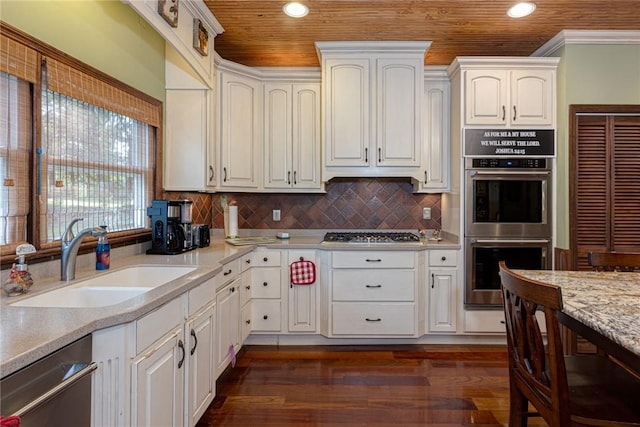 kitchen with dark wood finished floors, a sink, decorative backsplash, white cabinets, and appliances with stainless steel finishes