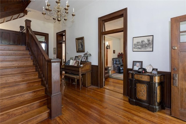 interior space with an inviting chandelier, wood finished floors, and wainscoting