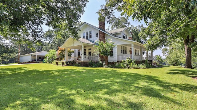 view of front facade featuring covered porch, a chimney, a front lawn, and metal roof