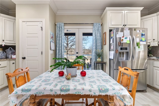 dining room featuring french doors, crown molding, and light wood-type flooring