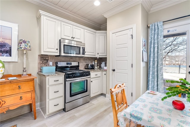 kitchen with white cabinetry, appliances with stainless steel finishes, crown molding, and decorative backsplash