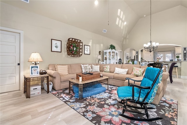 living room with a notable chandelier, high vaulted ceiling, and light hardwood / wood-style flooring