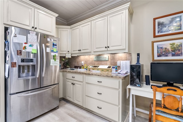 kitchen featuring stainless steel fridge, light stone counters, tasteful backsplash, ornamental molding, and white cabinets