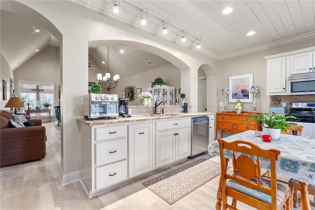 kitchen with sink, white cabinetry, light stone counters, pendant lighting, and stainless steel appliances