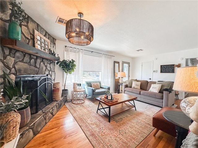 living area with visible vents, a fireplace, a textured ceiling, and wood finished floors