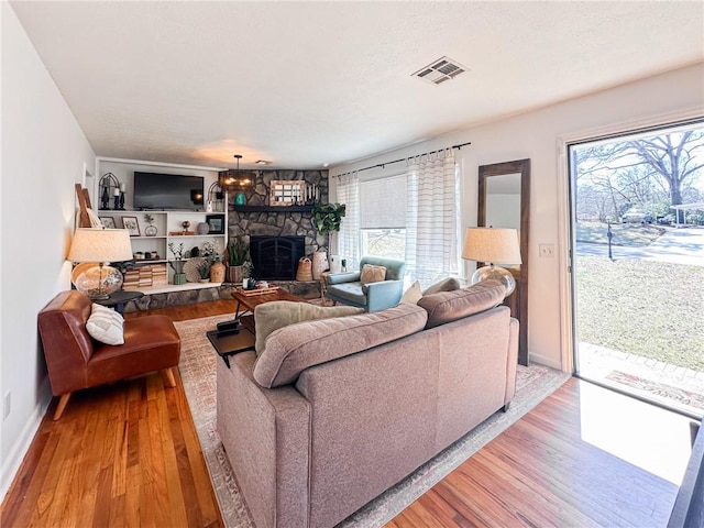 living room with a healthy amount of sunlight, a fireplace, visible vents, and wood finished floors