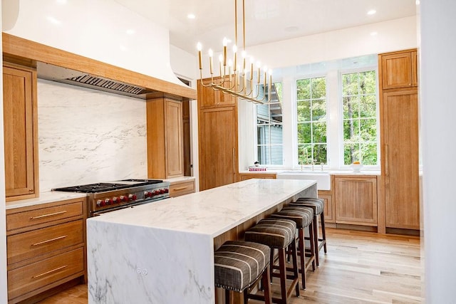 kitchen featuring decorative backsplash, stainless steel range, pendant lighting, a kitchen island, and a breakfast bar area