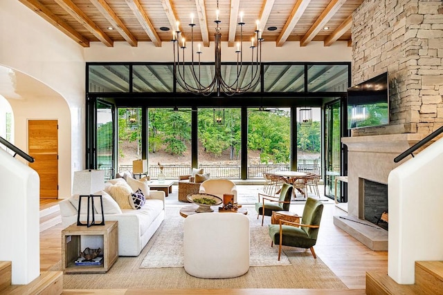 living room featuring a fireplace, light wood-type flooring, a towering ceiling, and wooden ceiling