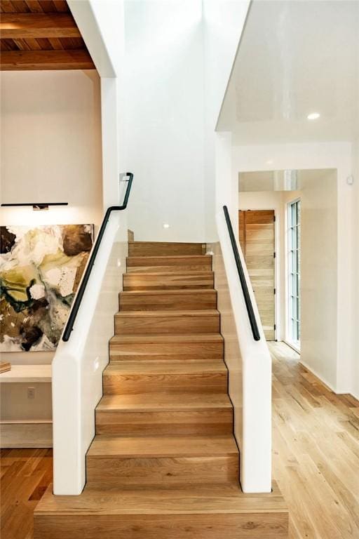 stairway featuring beam ceiling, wood ceiling, and wood-type flooring