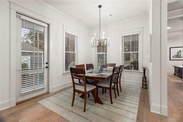 dining area featuring a chandelier, wood-type flooring, and ornamental molding