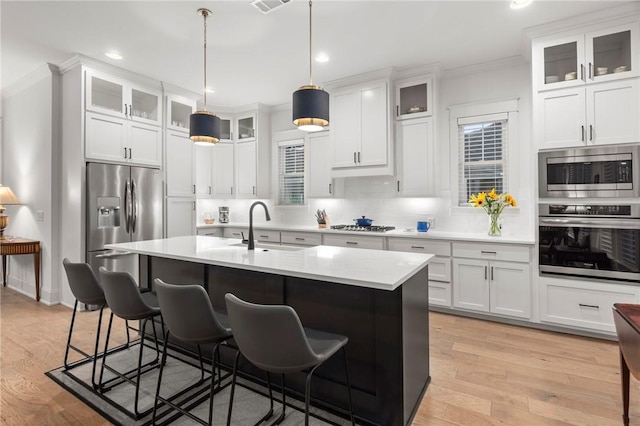 kitchen featuring backsplash, white cabinets, decorative light fixtures, and appliances with stainless steel finishes