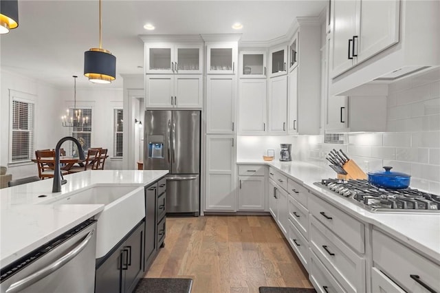 kitchen with backsplash, white cabinetry, hanging light fixtures, and appliances with stainless steel finishes