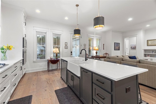 kitchen featuring sink, hanging light fixtures, an island with sink, white cabinetry, and stainless steel appliances