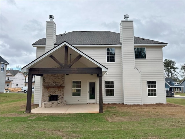 back of house featuring a lawn, a fireplace, and a patio