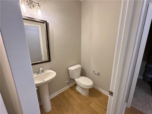 bathroom with wood-type flooring, toilet, and sink