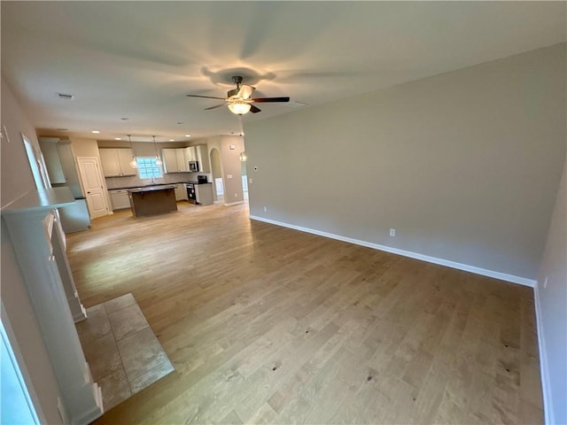 unfurnished living room with ceiling fan and light hardwood / wood-style flooring