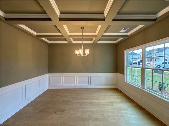 unfurnished room with light wood-type flooring, coffered ceiling, crown molding, a notable chandelier, and beamed ceiling