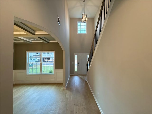 foyer entrance with beam ceiling, an inviting chandelier, coffered ceiling, and a healthy amount of sunlight