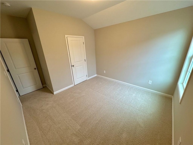 unfurnished bedroom with light carpet and vaulted ceiling