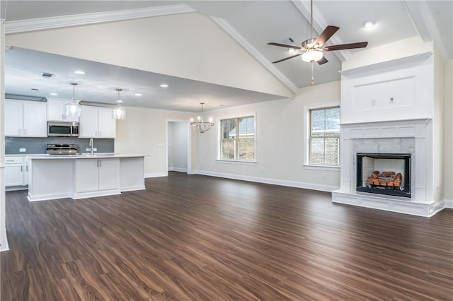 unfurnished living room with dark hardwood / wood-style floors, ornamental molding, a premium fireplace, and ceiling fan with notable chandelier