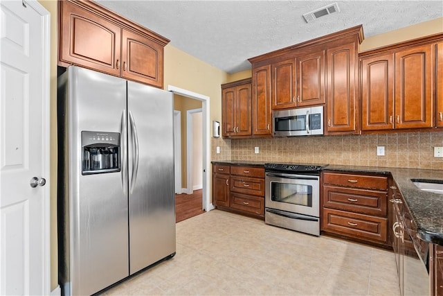 1817 Roanoke Ln, Auburn, AL 36830 - kitchen with appliances with stainless steel finishes, decorative backsplash, dark stone counters, and brown cabinets