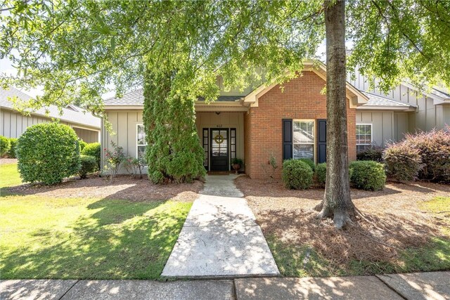 1630 Academy Dr Unit 402, Auburn, AL 36830 - view of front of house featuring board and batten siding, a front lawn, brick siding, and roof with shingles
