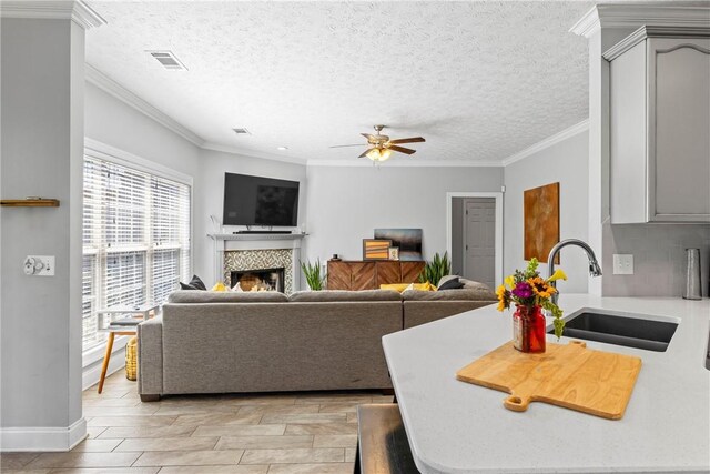 1630 Academy Dr Unit 402, Auburn, AL 36830 - living room featuring a fireplace, a ceiling fan, light wood-style floors, ornamental molding, and a textured ceiling