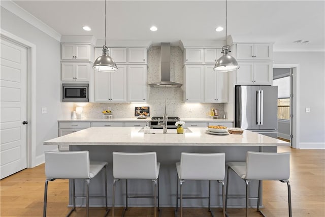 kitchen with wall chimney exhaust hood, ornamental molding, white cabinetry, and stainless steel appliances