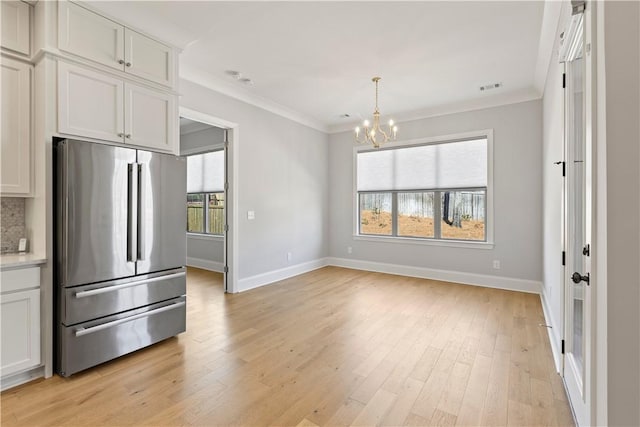 kitchen featuring light wood finished floors, baseboards, decorative backsplash, freestanding refrigerator, and crown molding