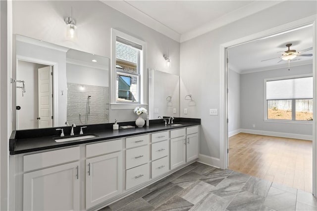 bathroom featuring crown molding, a sink, baseboards, and double vanity