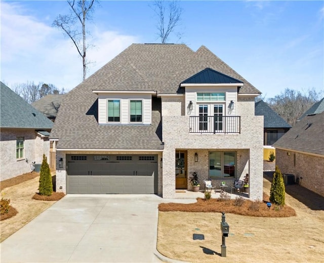 view of front of home with brick siding, driveway, a balcony, and roof with shingles