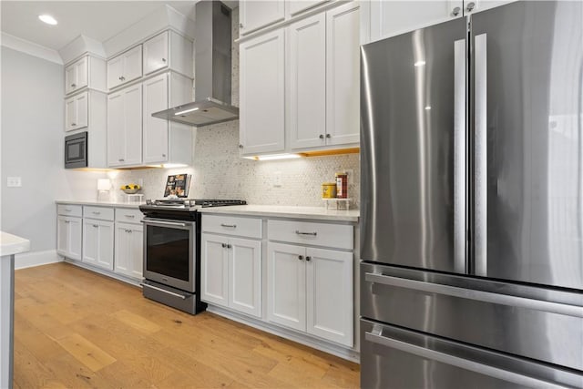 kitchen with stainless steel appliances, wall chimney exhaust hood, light countertops, and backsplash