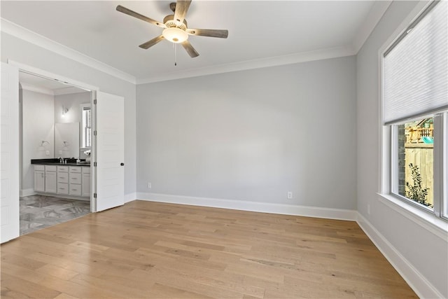 empty room featuring light wood-style floors, a ceiling fan, baseboards, and crown molding