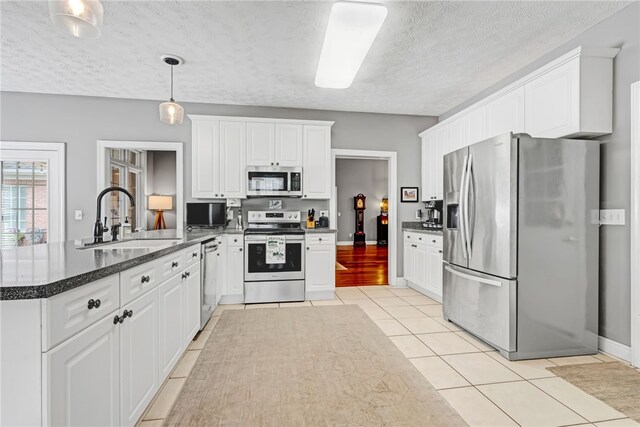 1939 Windway Rd, Auburn, AL 36830 - kitchen featuring appliances with stainless steel finishes, a sink, a peninsula, light tile patterned flooring, and a textured ceiling