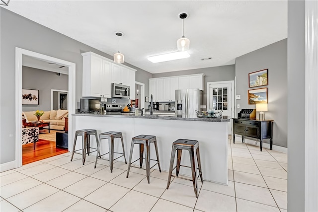 1939 Windway Rd, Auburn, AL 36830 - kitchen with stainless steel appliances, a kitchen bar, a peninsula, dark countertops, and white cabinetry