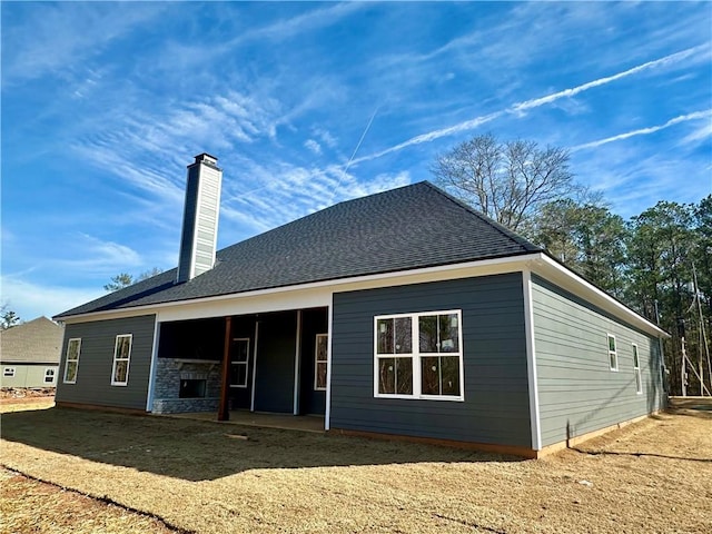 rear view of house with a patio, a shingled roof, and a chimney