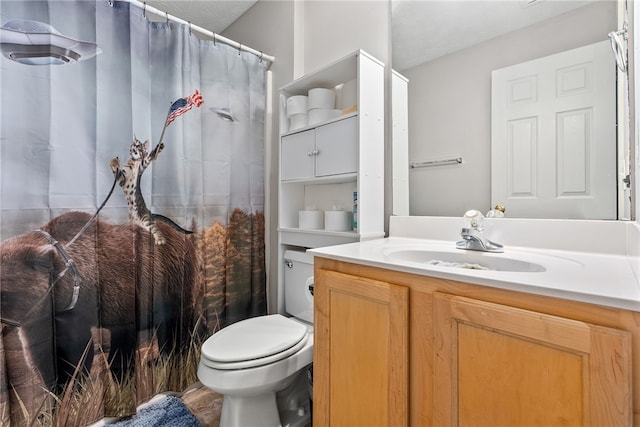 bathroom with a textured ceiling, vanity, and toilet