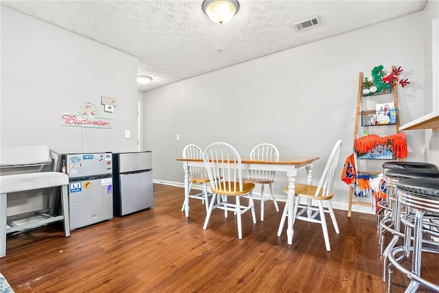 dining area with wood-type flooring and a textured ceiling