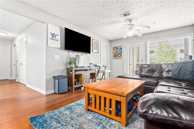 living room with wood-type flooring, a textured ceiling, and ceiling fan