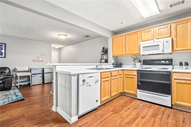 kitchen featuring a textured ceiling, light wood-type flooring, white appliances, and kitchen peninsula