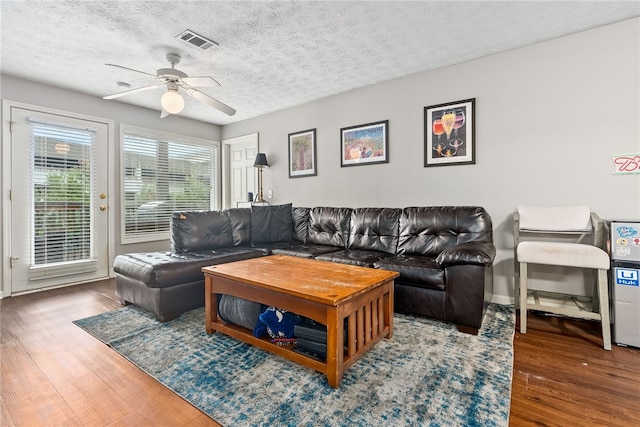 living room featuring ceiling fan, dark hardwood / wood-style floors, and a textured ceiling