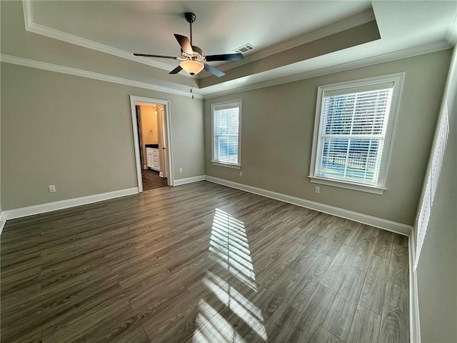 unfurnished room with a raised ceiling, crown molding, dark hardwood / wood-style flooring, and ceiling fan