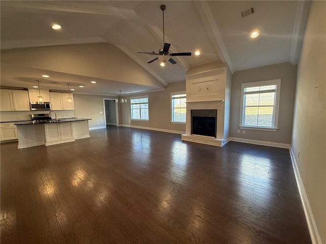 unfurnished living room featuring lofted ceiling, sink, ceiling fan, dark hardwood / wood-style floors, and a fireplace