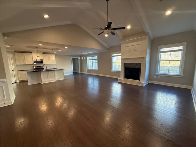 unfurnished living room featuring dark hardwood / wood-style floors, vaulted ceiling, ceiling fan, and sink