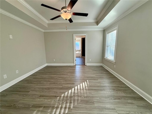 unfurnished room featuring a raised ceiling, ceiling fan, crown molding, and hardwood / wood-style flooring